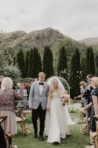 Bride and groom exchanging walking down the outdoor aisle after the ceremony.