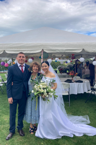 The bride and groom and Debbie outside the tent.