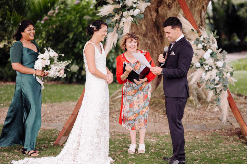 Bride and Groom exchanging vows with brides maid and celebrant looking on.