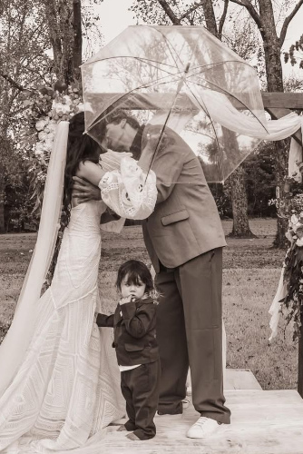 The bride and groom kissing after the ceremony and with a young child.