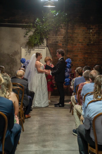 The bride and groom with a rustic red brick wall behind them.
