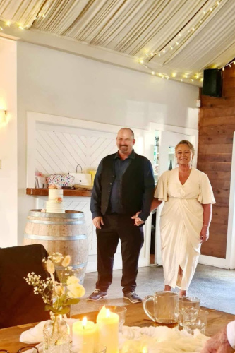 The bride and groom in a homely venue holding hands.